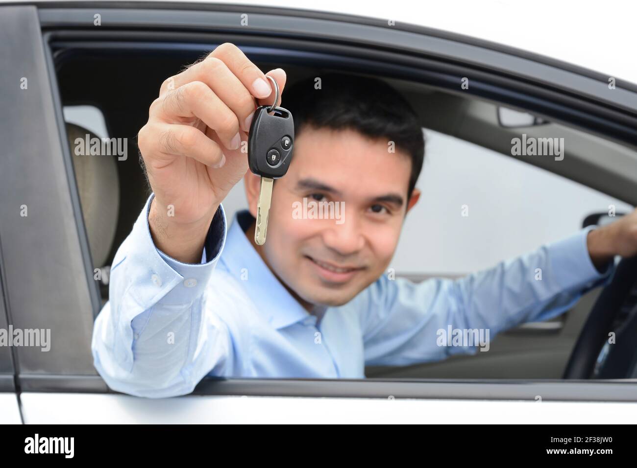 Smiling asian man as a driver showing car key (key focused Stock Photo