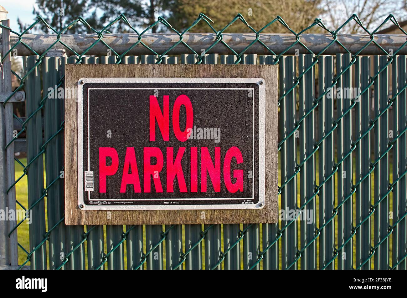 No Parking sign on a green chain link fence. Stock Photo