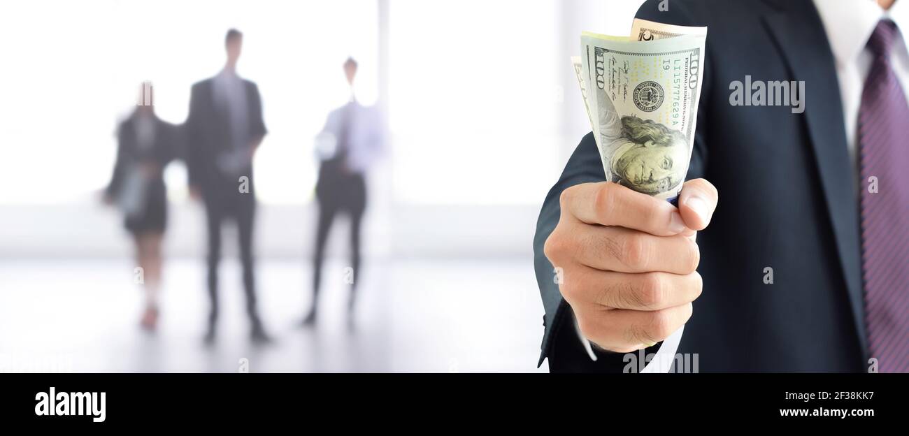 Businessman holding money, United States Dollar (USD) banknotes, in his fist - business and financial panoramic header background Stock Photo