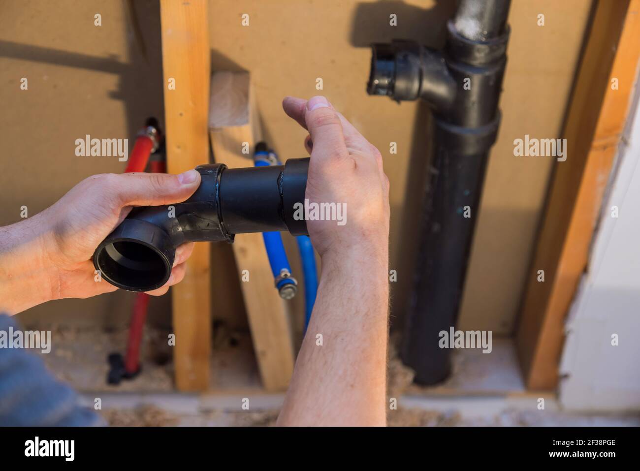 Plumber joining PVC sewage drain pipes on a home under construction Stock Photo