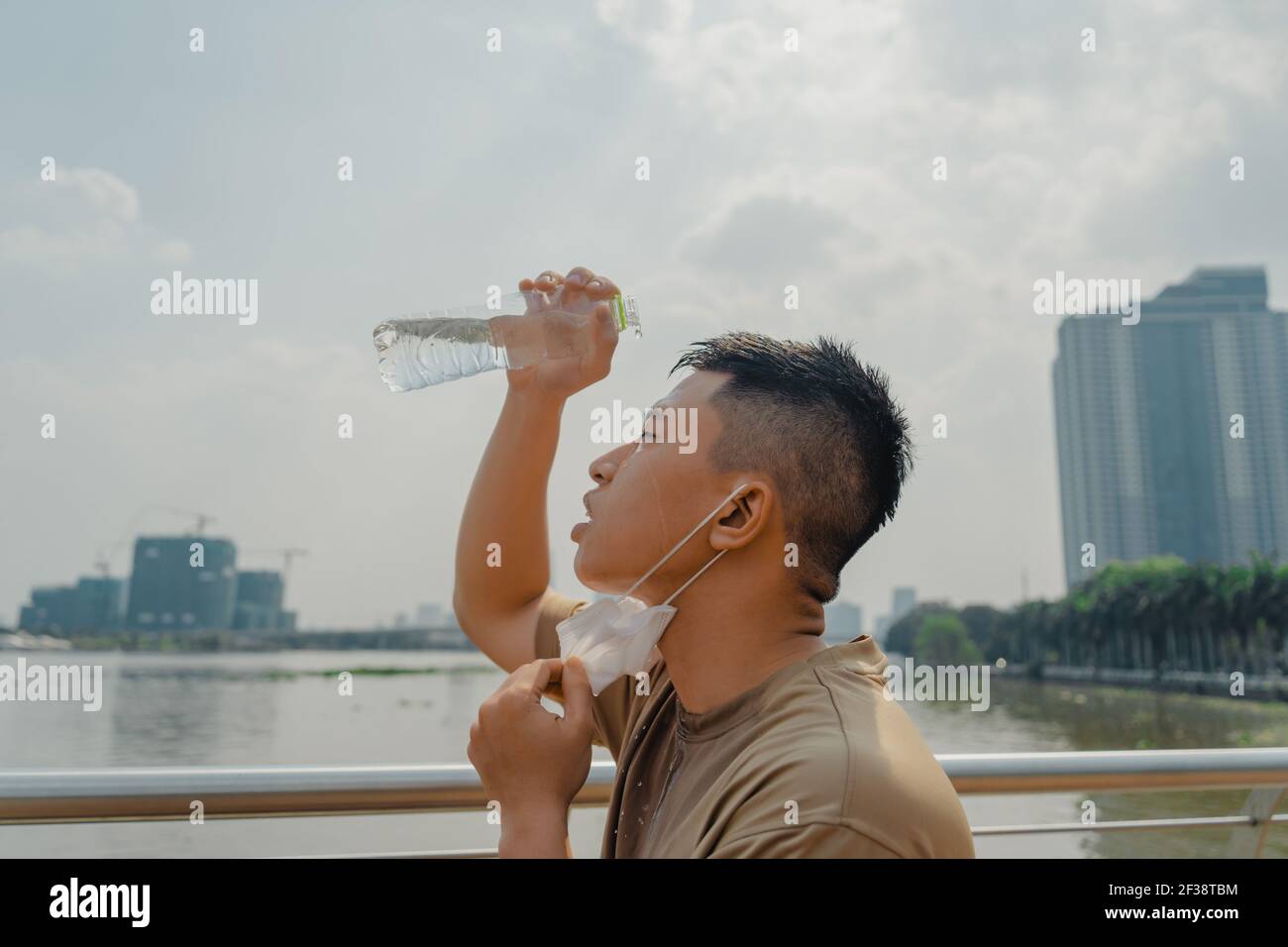 Young asian runner man putting off face mask while using water in bottle to  wash his face after finished running and working out. He wearing medical m  Stock Photo - Alamy