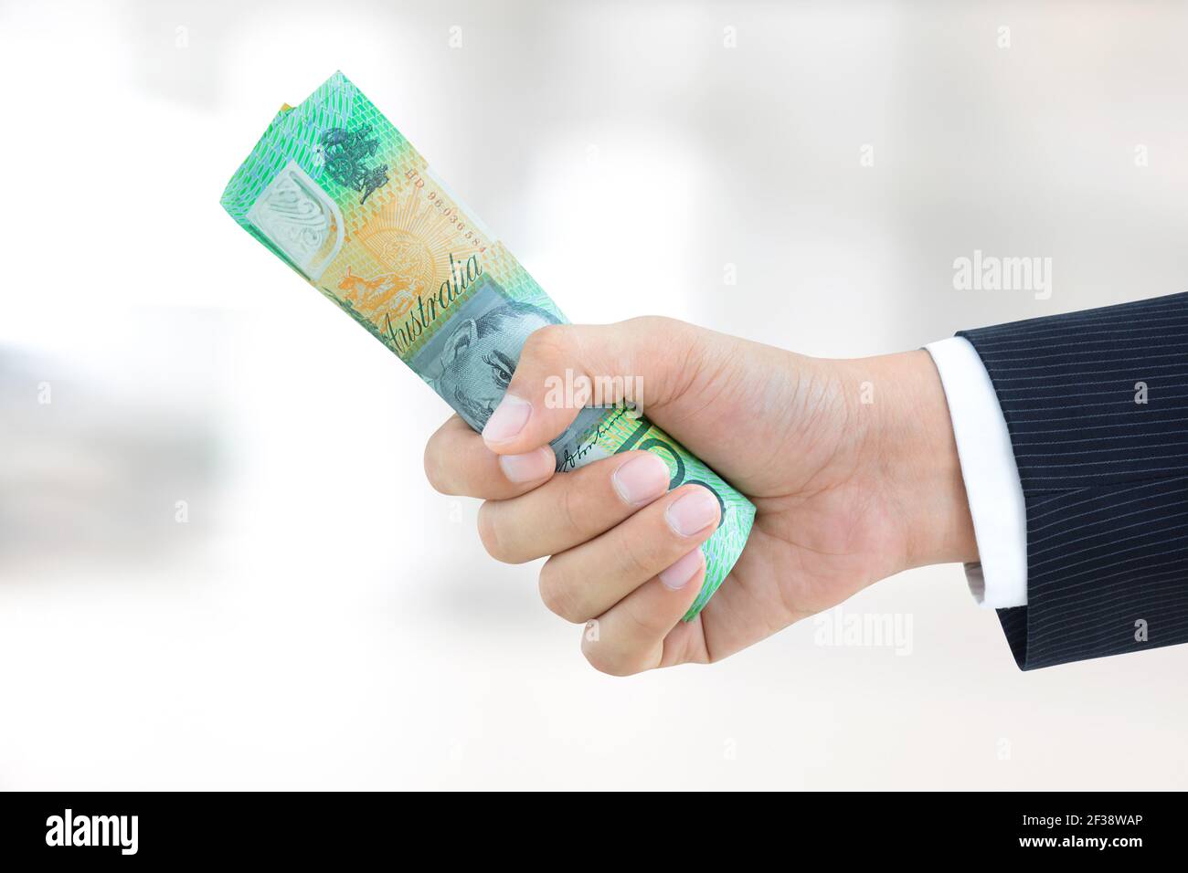 Hand of businessman  giving roll of money, Australian dollar (AUD) banknotes Stock Photo