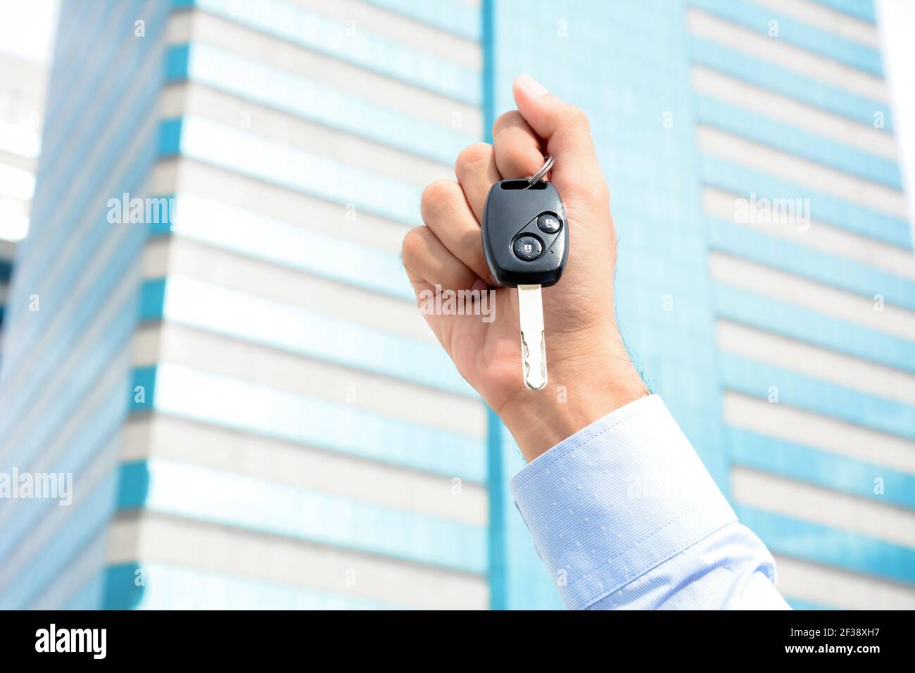 Hand holding car key on building background Stock Photo - Alamy