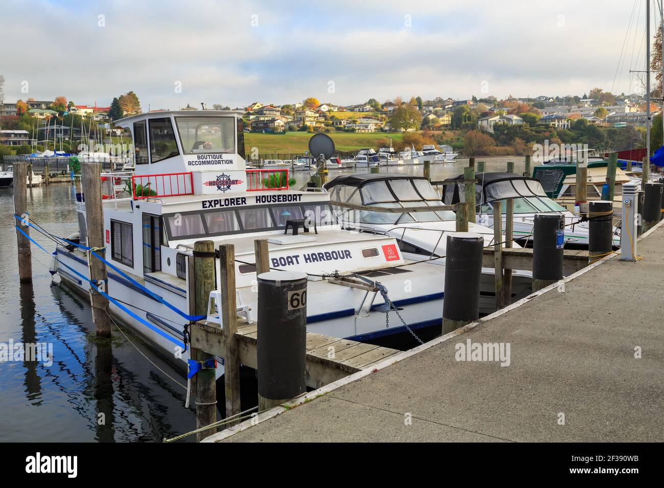 A marina in Taupo, New Zealand. There is a houseboat for rent, with an Airbnb logo Stock Photo