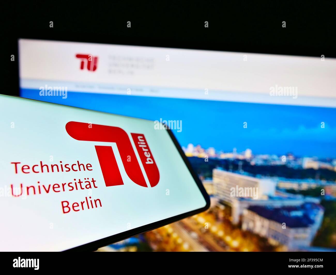 Mobile phone with logo of German education institution Technical University of Berlin on screen in front of website. Focus on center of phone display. Stock Photo