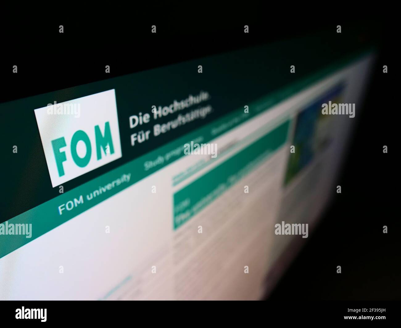 High angle view of website with logo of FOM University of Applied Sciences for Economics and Management on monitor. Focus on top-left of screen. Stock Photo