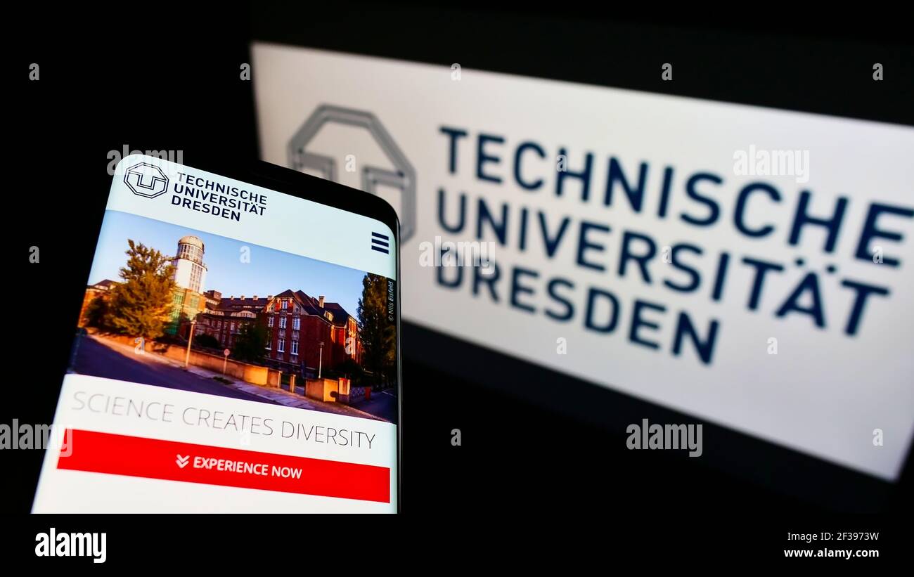 Cellphone with webpage of German education institution Dresden University of Technology on screen in front of logo. Focus on top-left of phone. Stock Photo