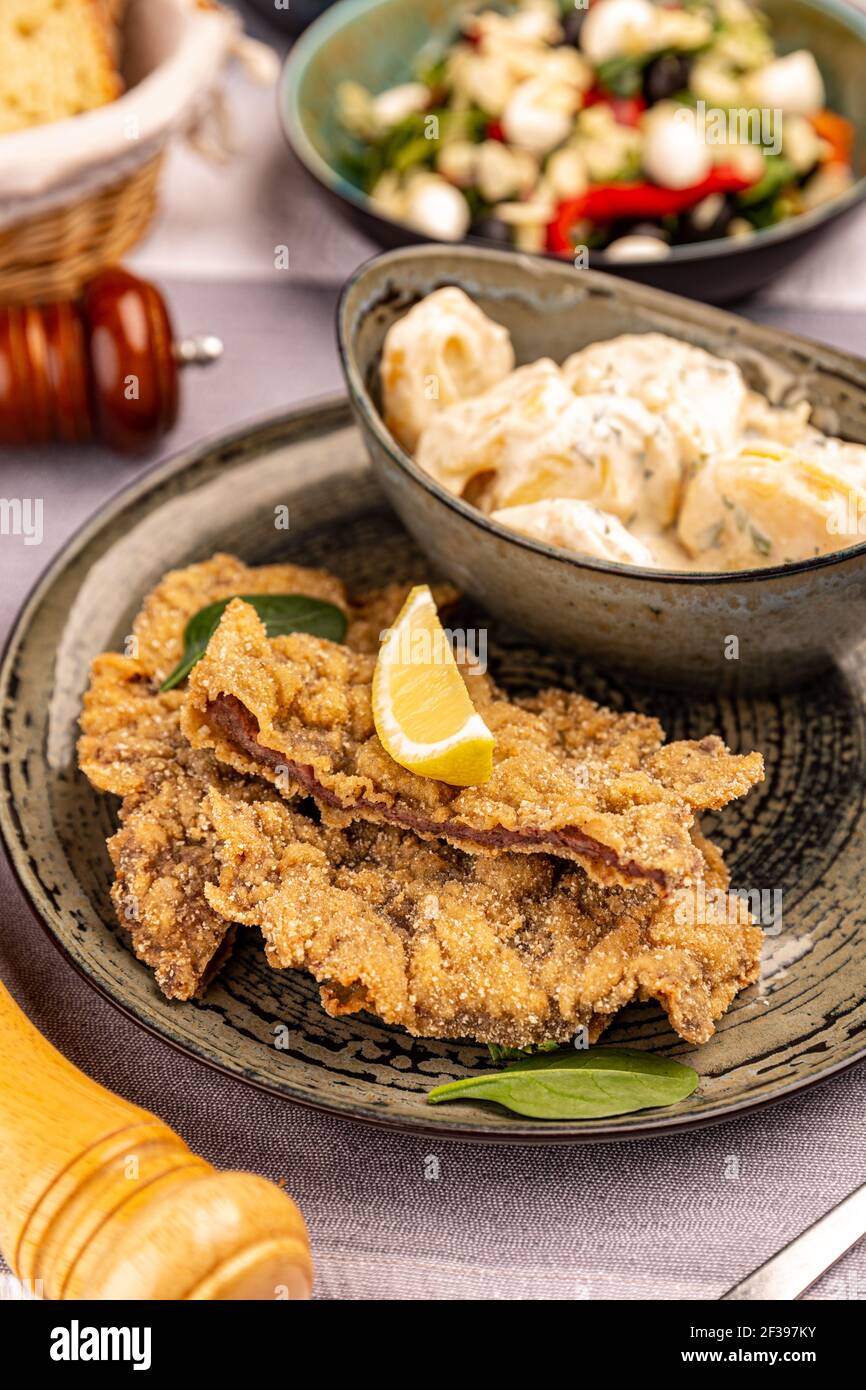 Schnitzel with potato salad served on the restaurant table Stock Photo