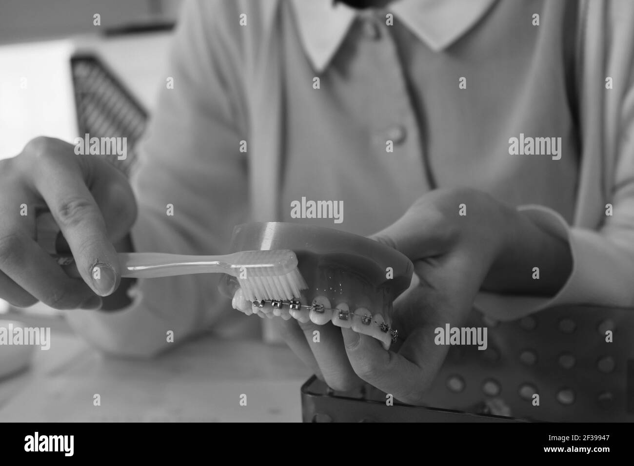 Black and white view of dental nurse showing how to brush with braces Stock Photo