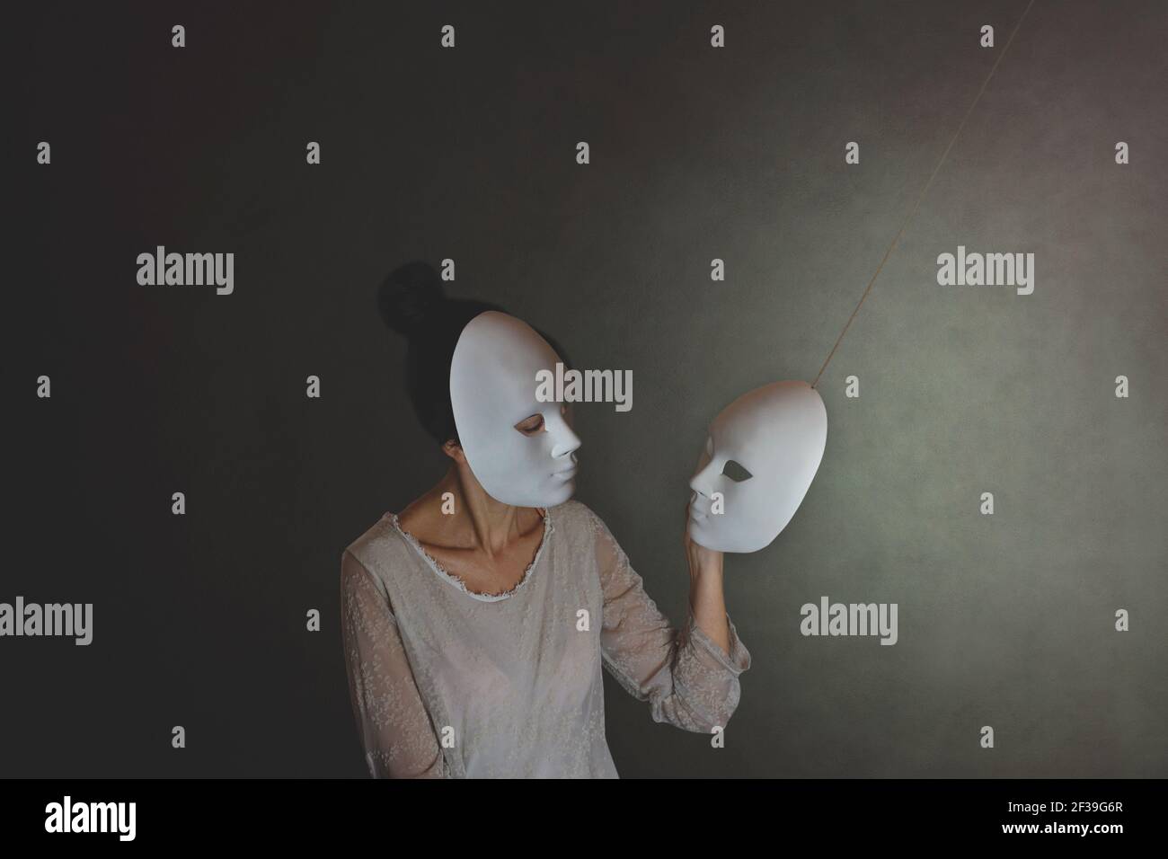 woman with mask chooses another mask of herself, the concept of introspection Stock Photo