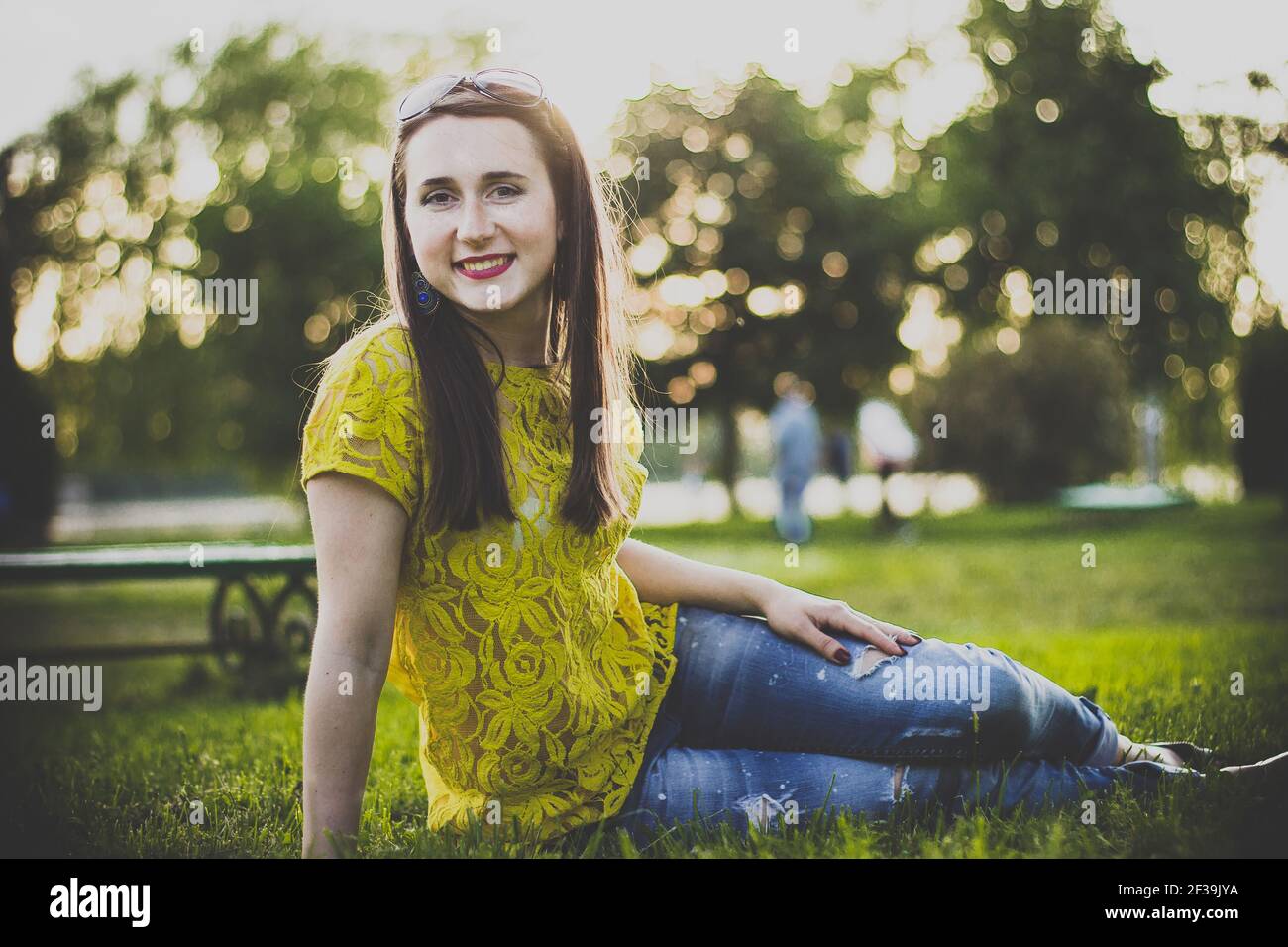 Happy woman sitting on the grass in the evening Stock Photo