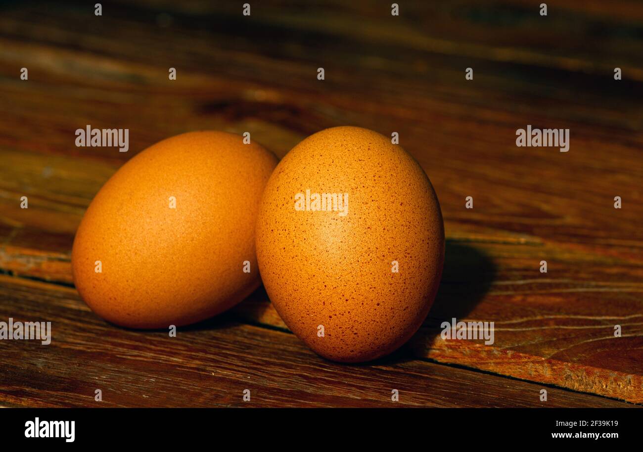 Two chicken eggs on the old teak table, in shallow focus Stock Photo
