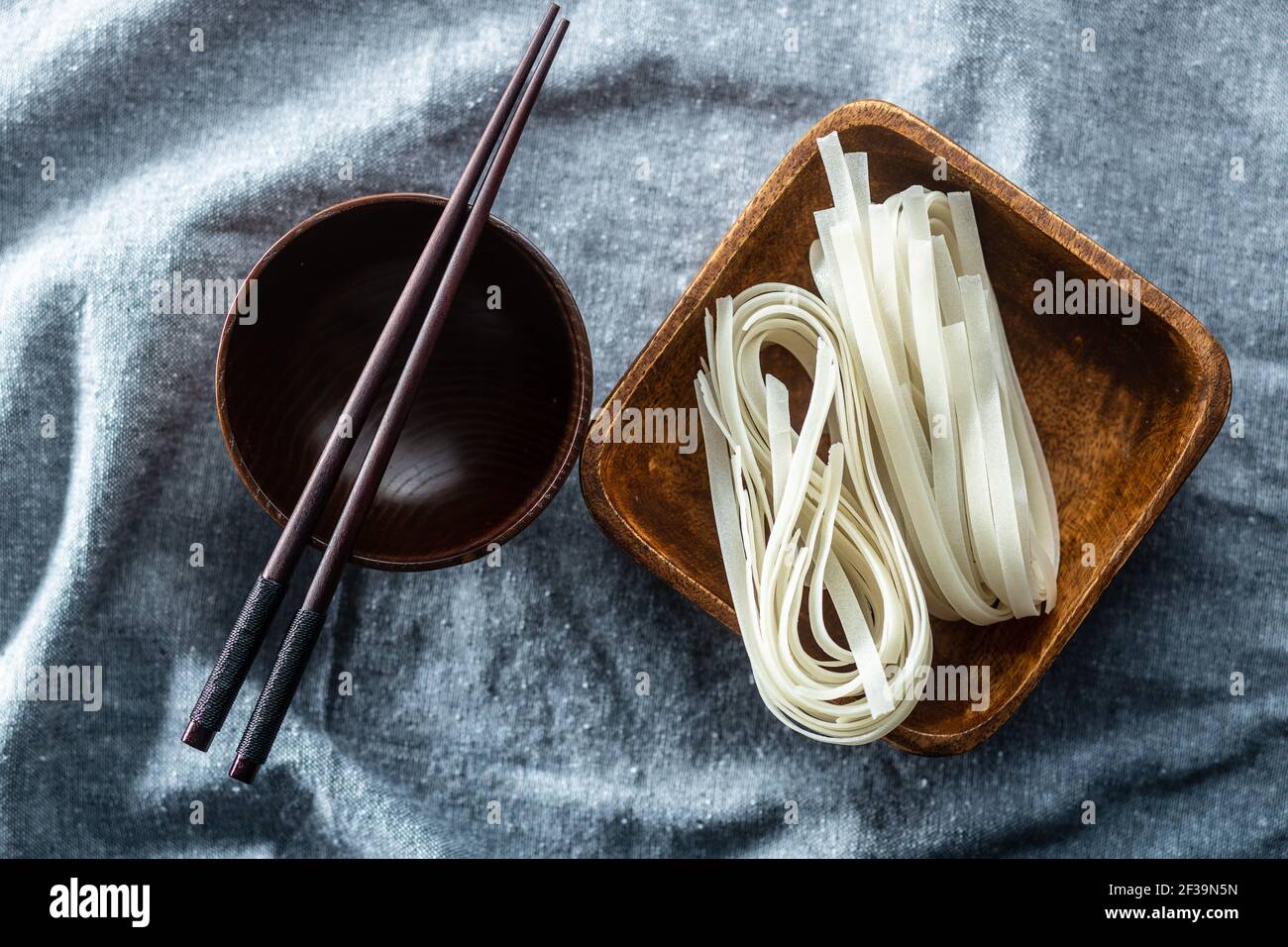 Dried white rice noodles. Raw pasta. Uncooked noodles in wooden bowl