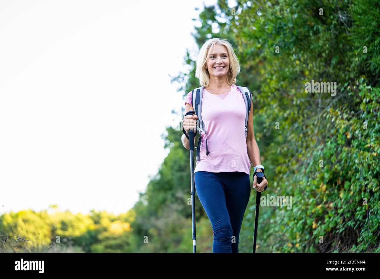 Low angle view of smiling mature woman hiking in forest Stock Photo
