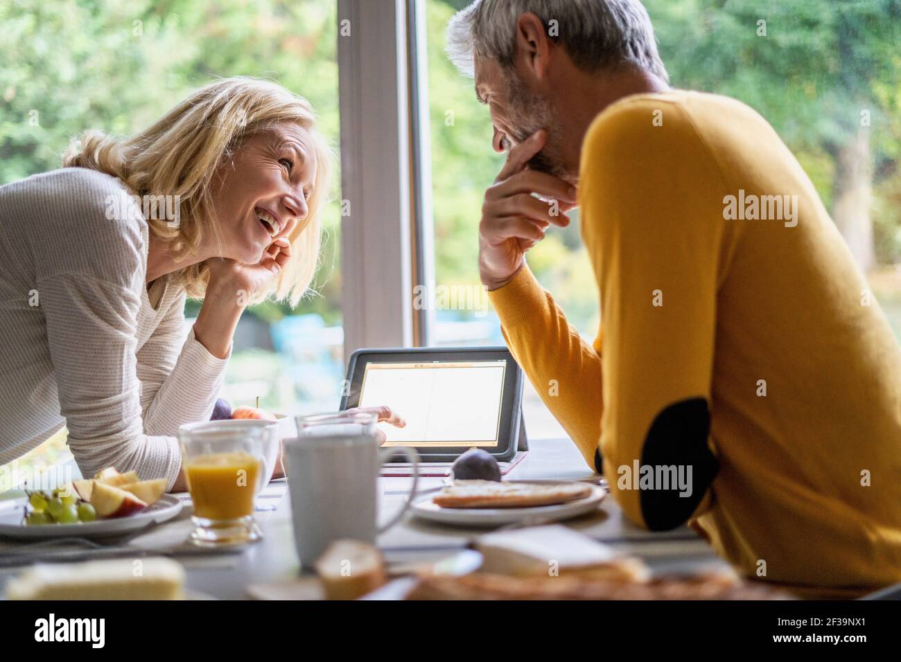 Smiling mature couple using digital tablet while having breakfast Stock Photo