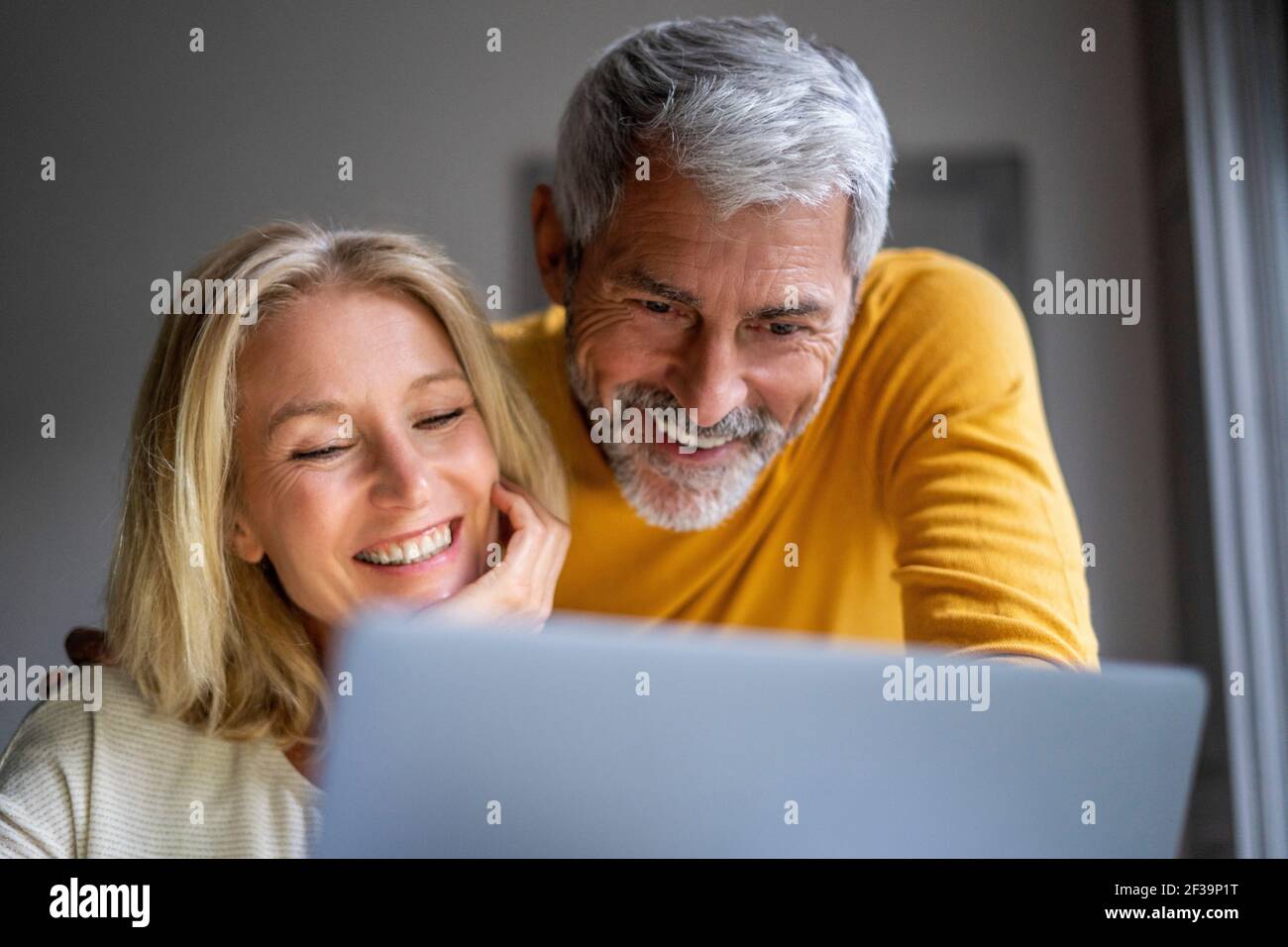 Smiling mature couple using laptop Stock Photo