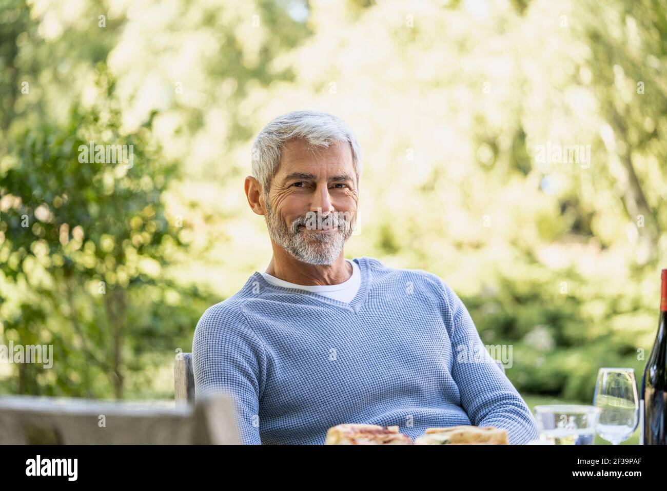 Portrait of smiling mature man sitting on chair Stock Photo - Alamy