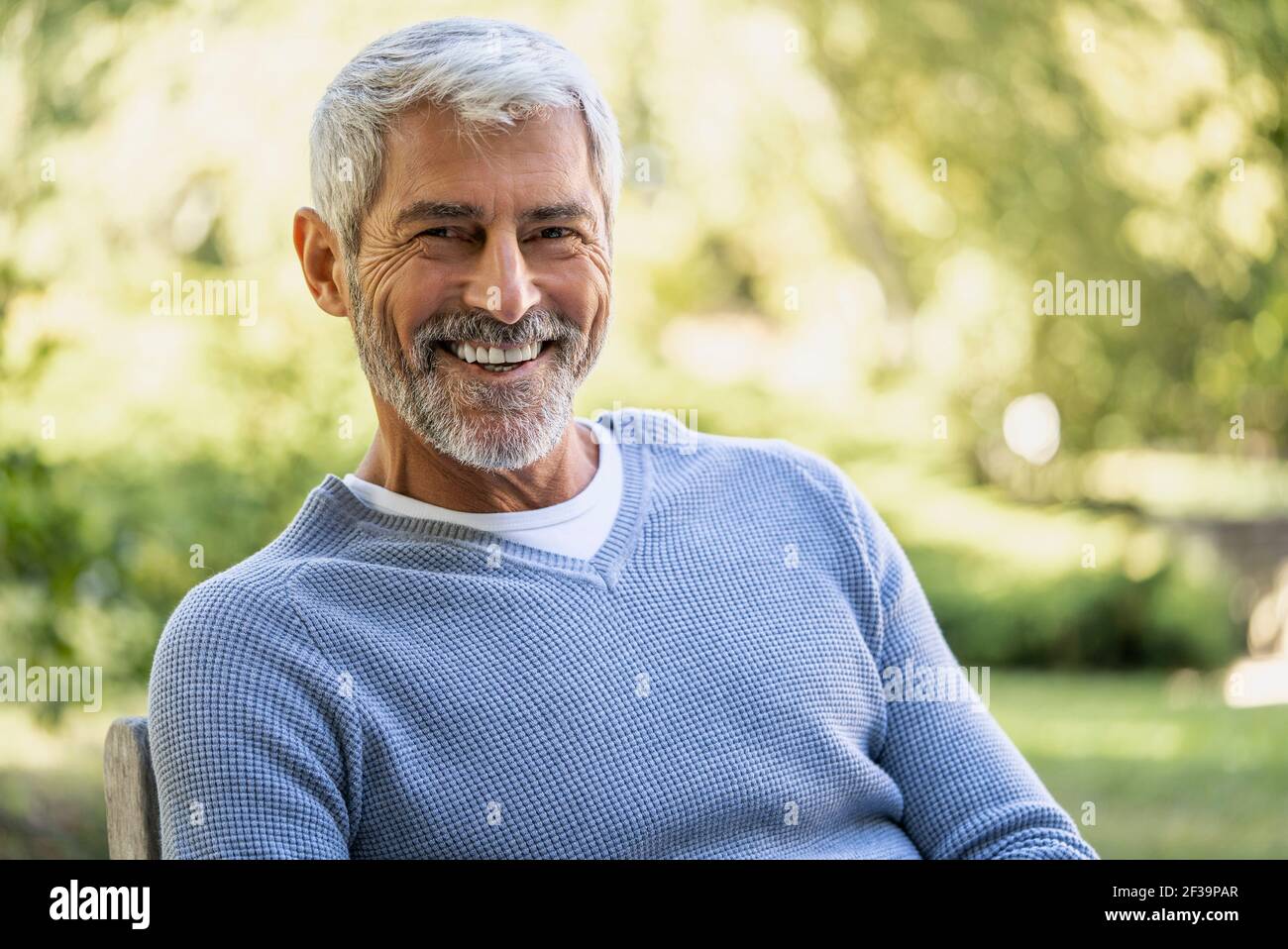 Portrait of smiling mature man sitting on chair Stock Photo - Alamy