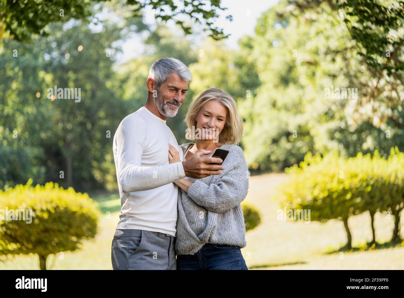 Smiling mature couple using smartphone in backyard Stock Photo