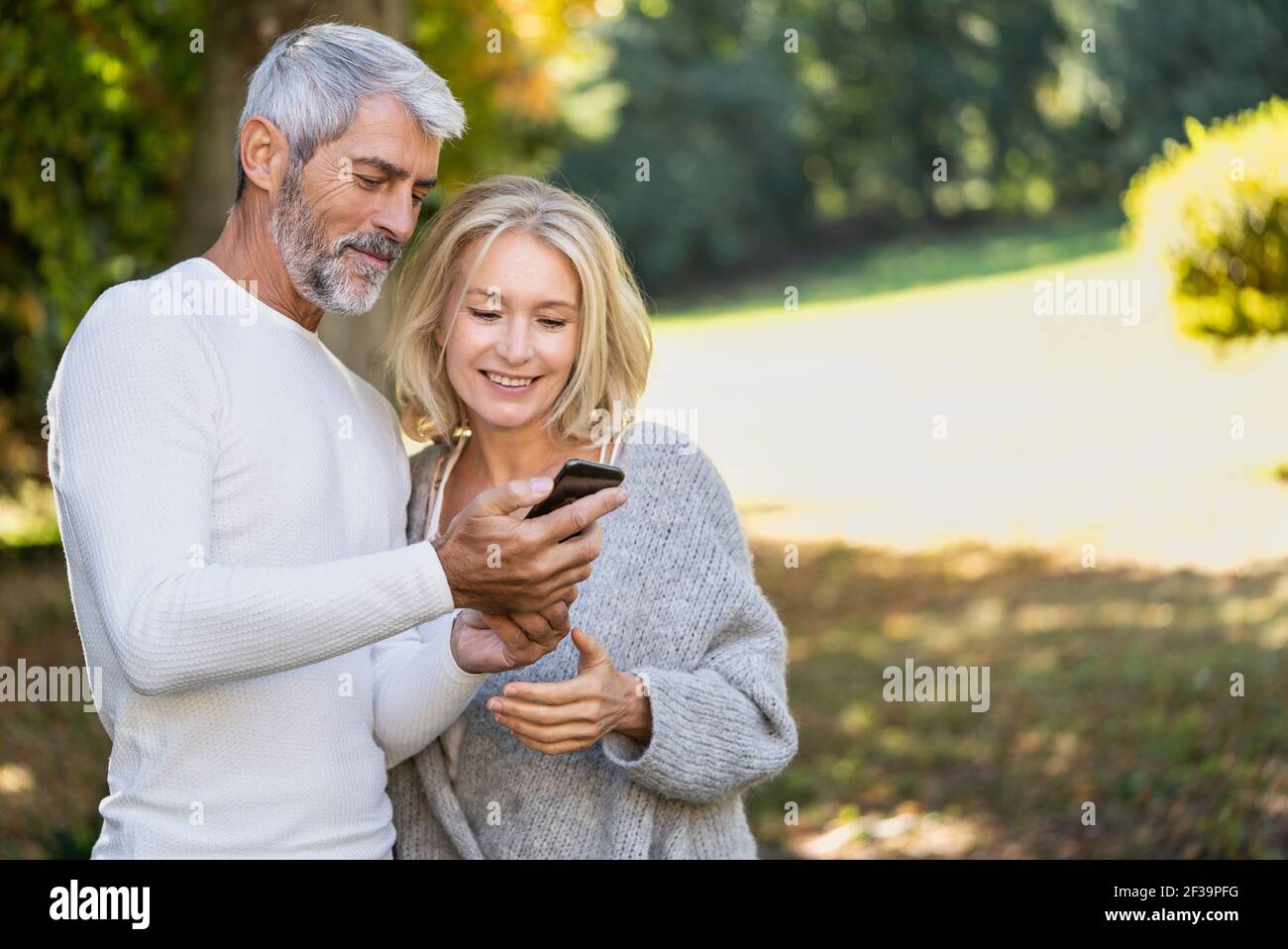 Smiling mature couple using smartphone in backyard Stock Photo