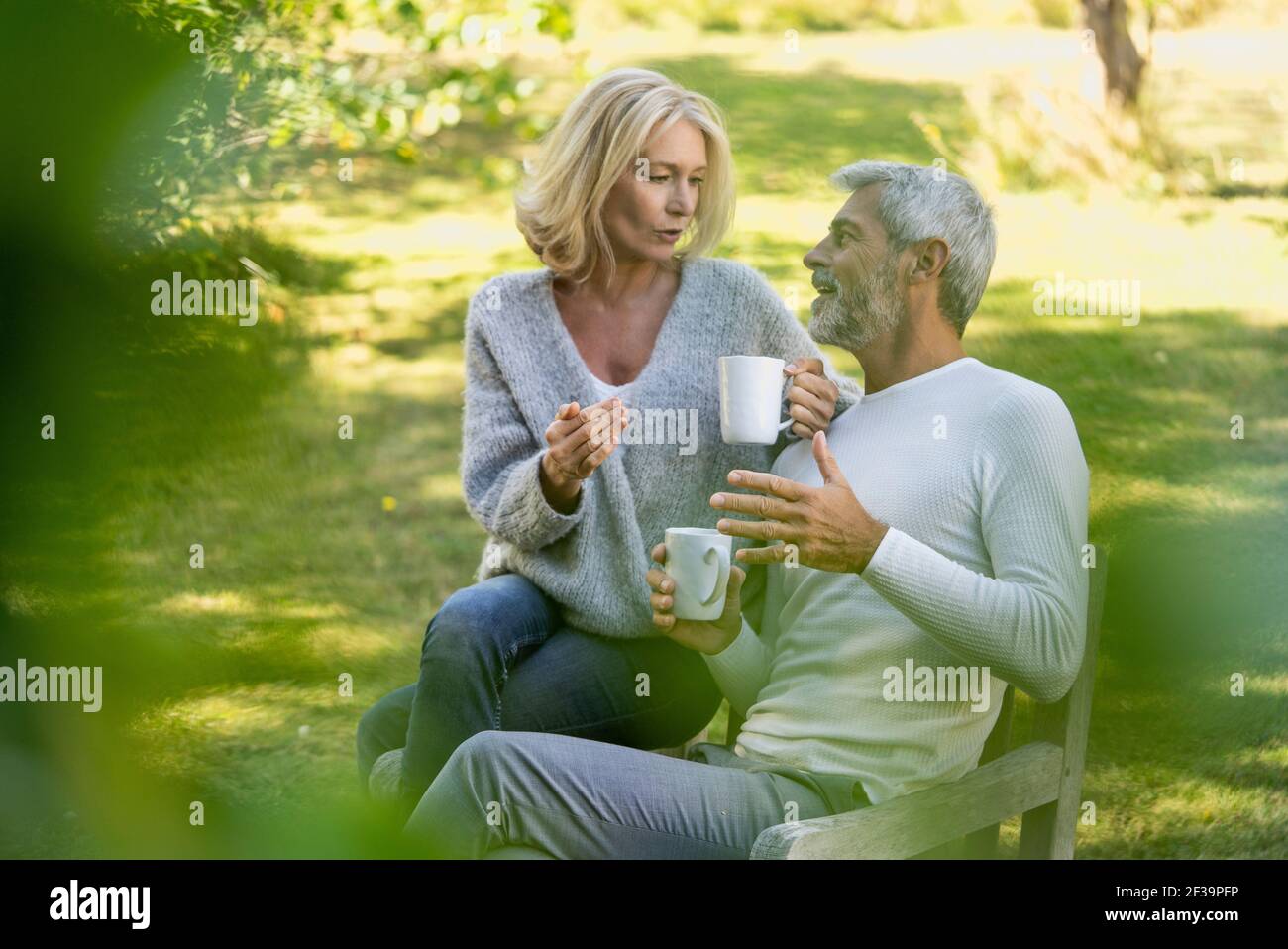 Mature couple talking while having coffee in backyard Stock Photo