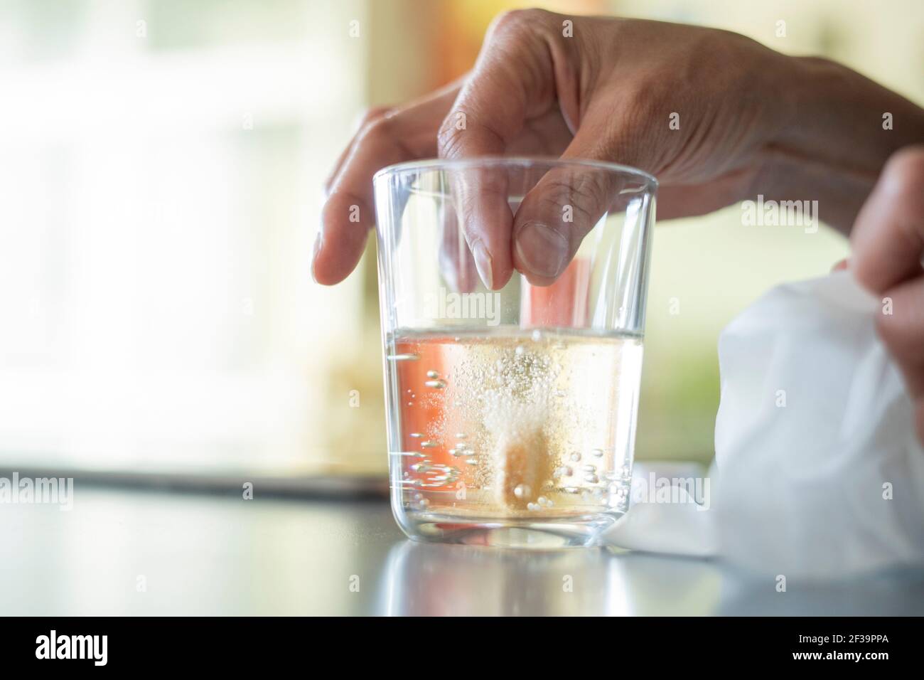 Close-up of woman's hand dropping pill in glass of water Stock Photo