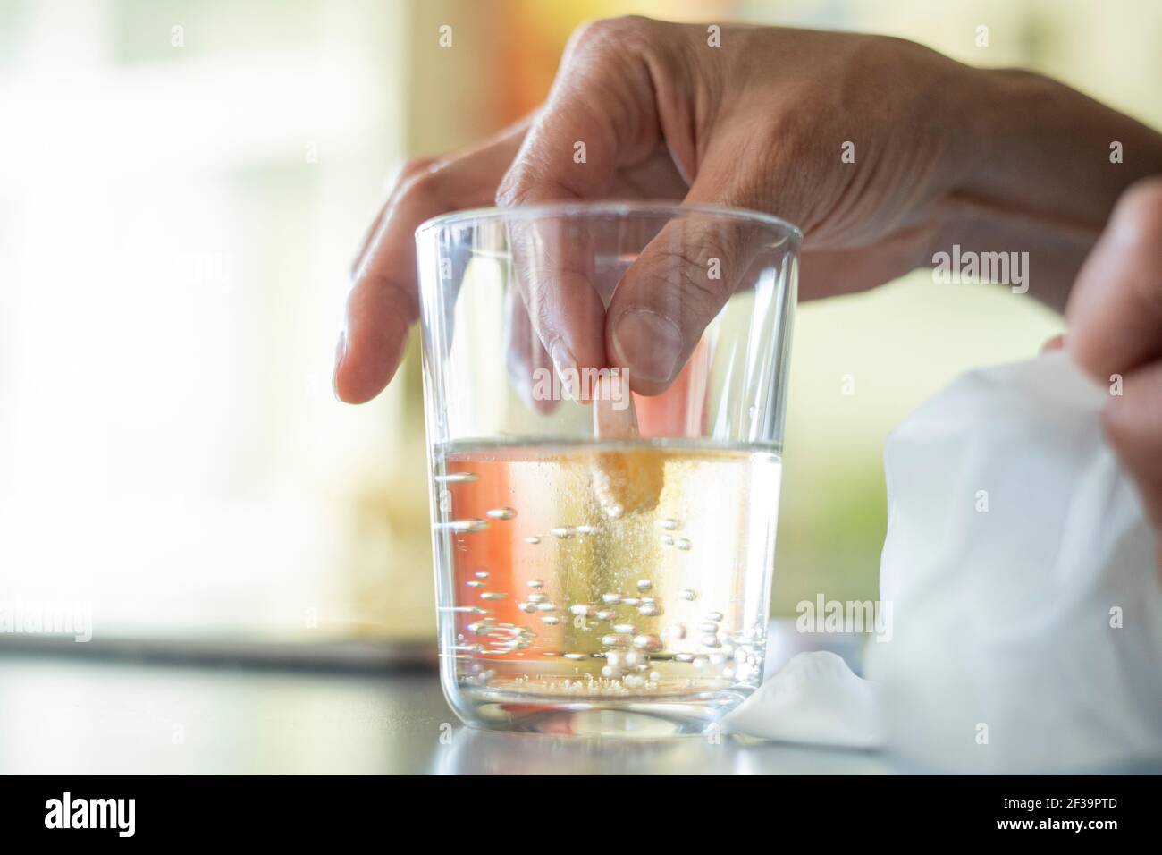 Close-up of woman's hand holding pill in glass of water Stock Photo