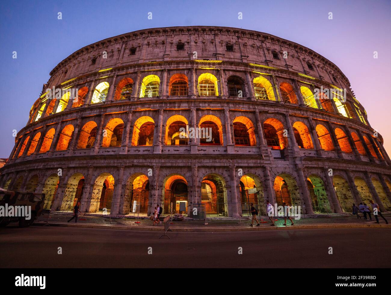Low angle view of tourists walking on street outside Colosseum at dusk, Rome Stock Photo