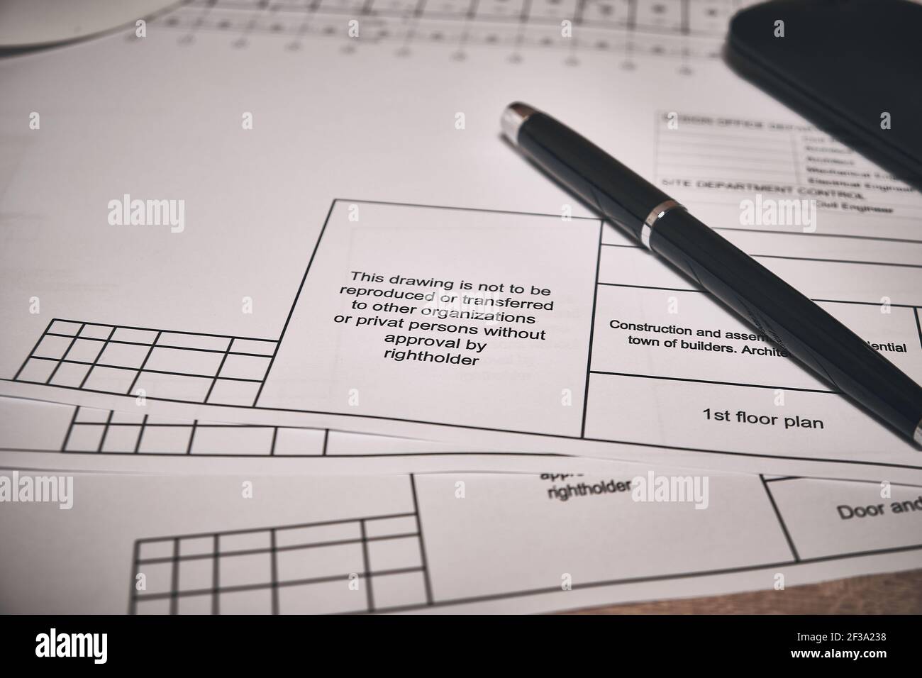 Engineering drawings and black pen at desk Stock Photo