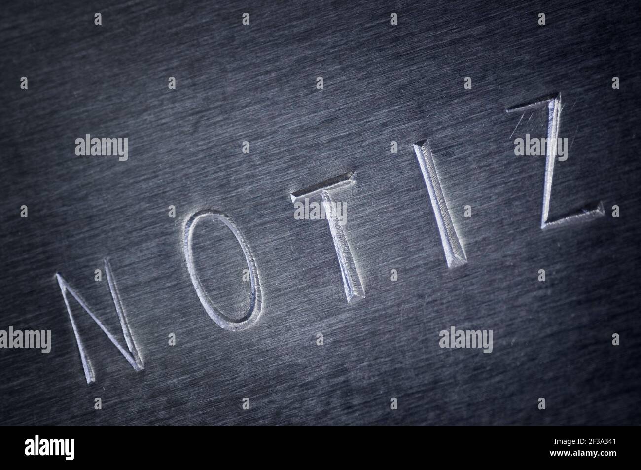 Close-up of a gray bevelled metal plate with the word NOTE stamped on it diagonally. Stock Photo