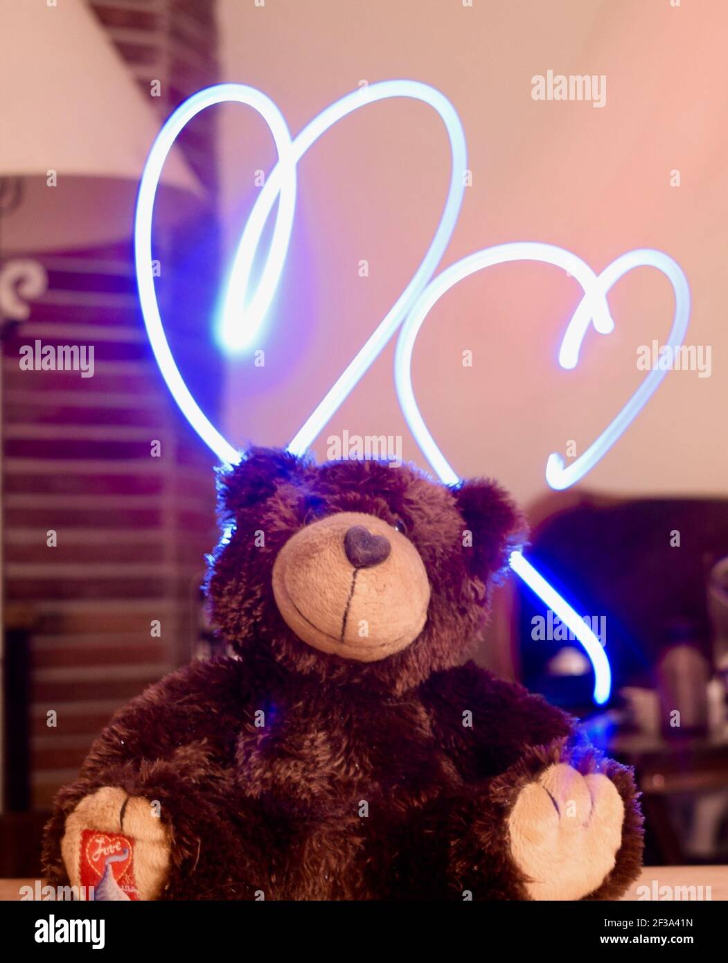 FRESNO, UNITED STATES - Apr 23, 2016: A photo of a light painting of two hearts over a cute stuffed colored brown bear in the home Stock Photo