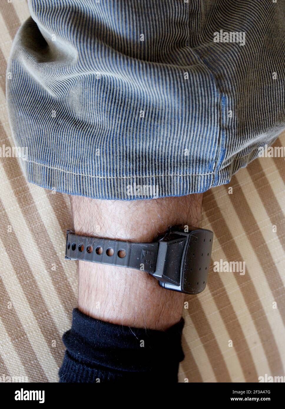 Person who has an electronic electronic ankle bracelet on one leg after a conditional release from prison. Stock Photo