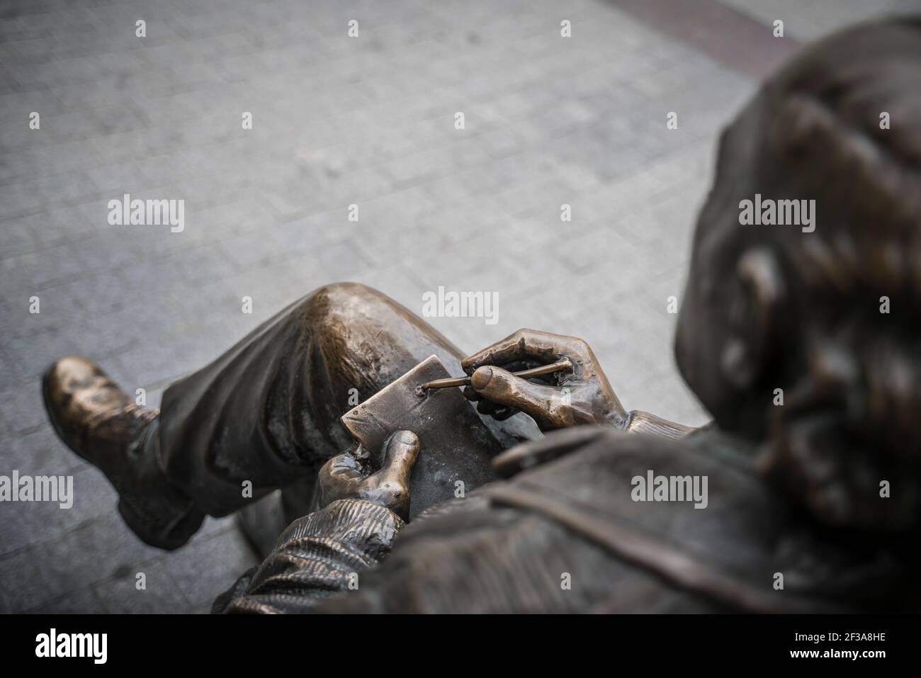 Bronze statue sitting on a bench Stock Photo