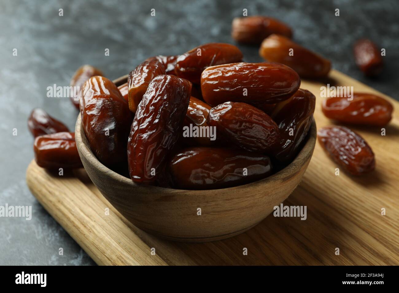 Board with bowl of dried dates on black smokey background Stock Photo ...