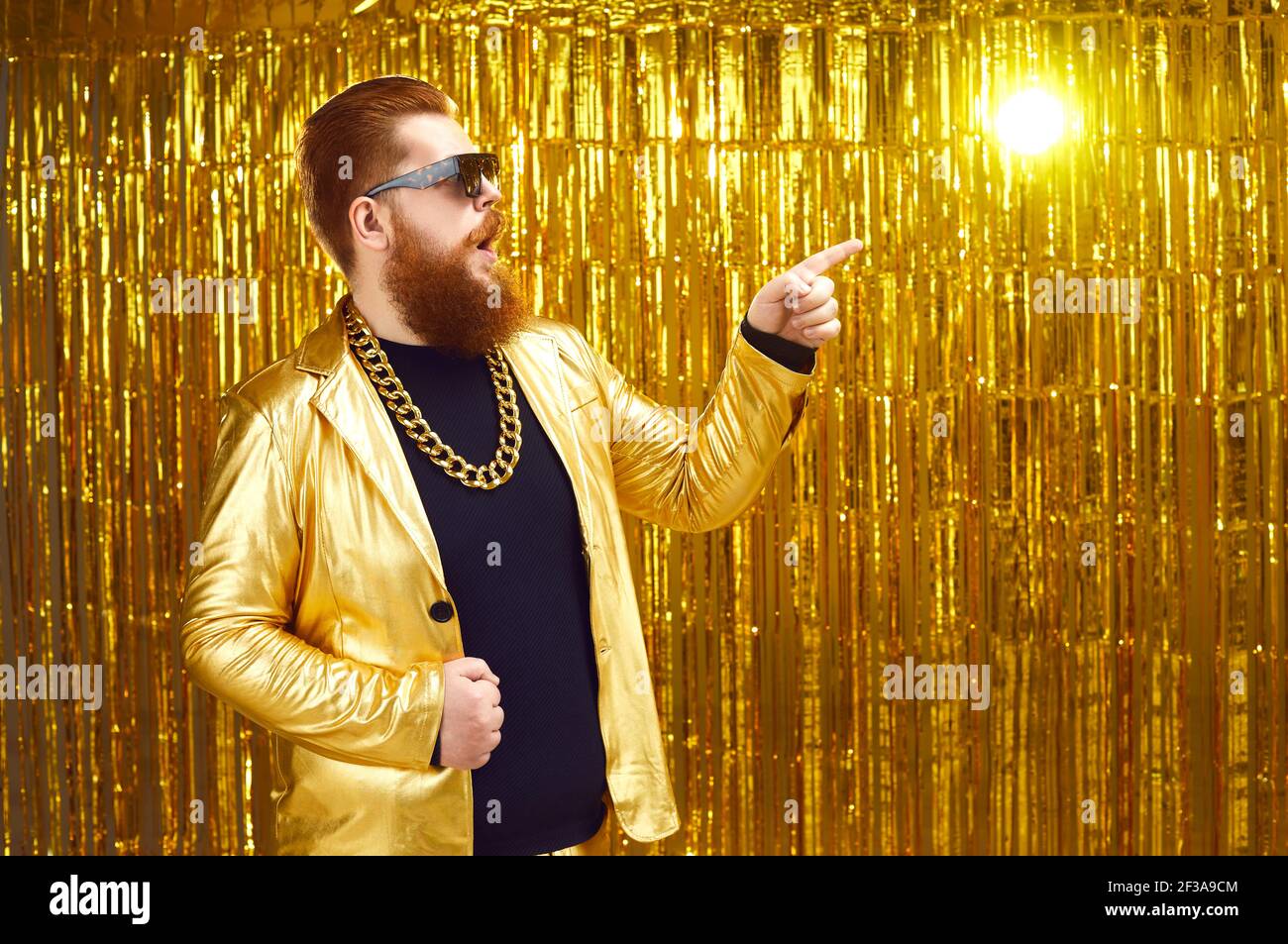Surprised man in party jacket and gold chain pointing away to advertising copy space Stock Photo
