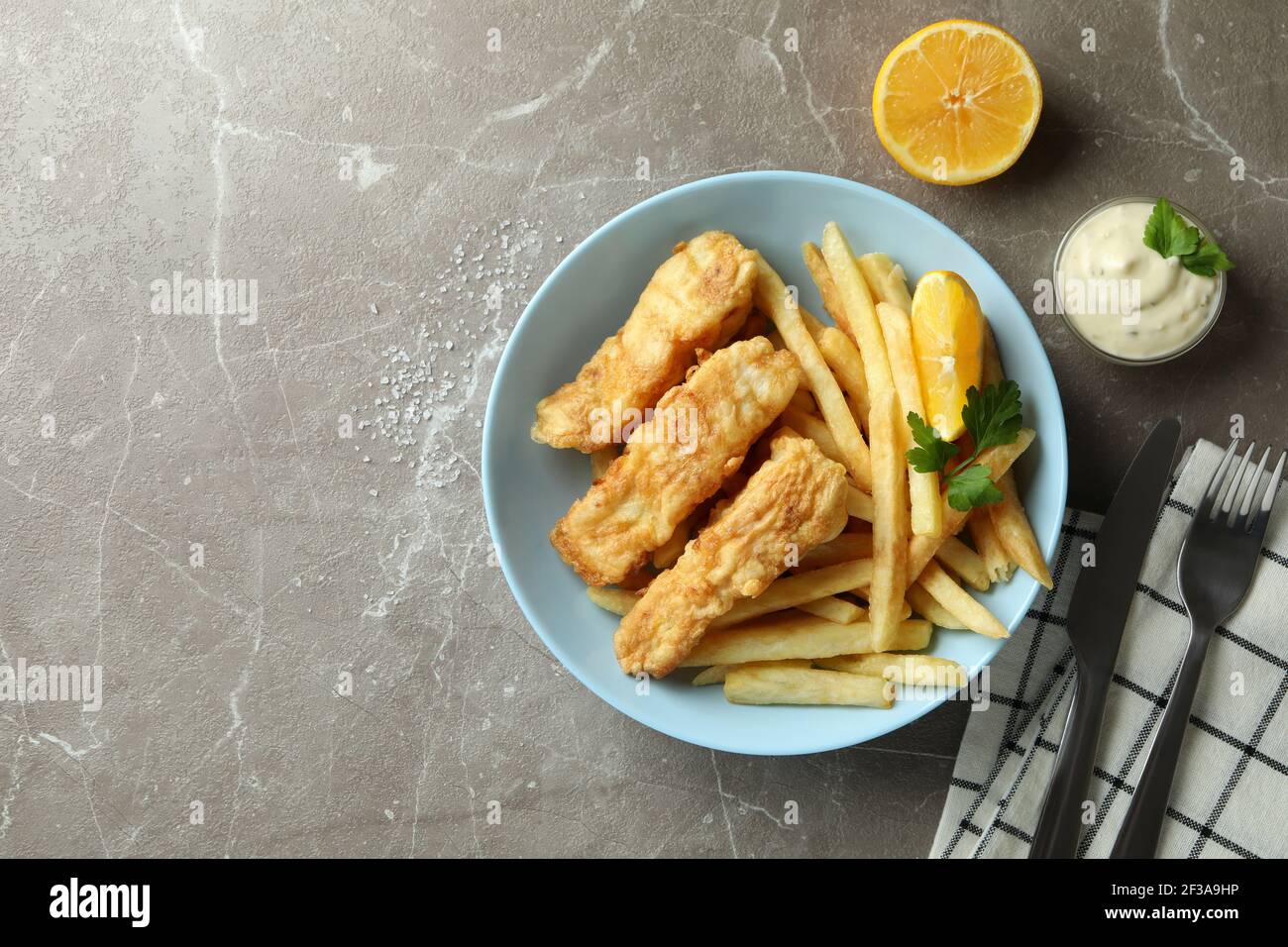 Concept of tasty eating with fried fish and chips on gray textured table Stock Photo