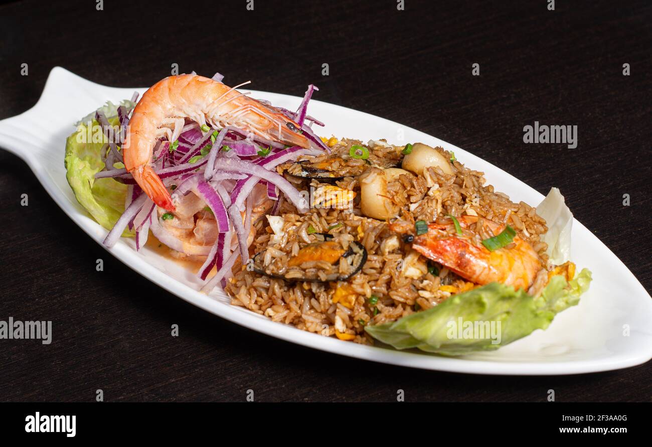 Peruvian traditional food. Seafood with rice decorated with red onion, lettuce. Arroz con mariscos Stock Photo