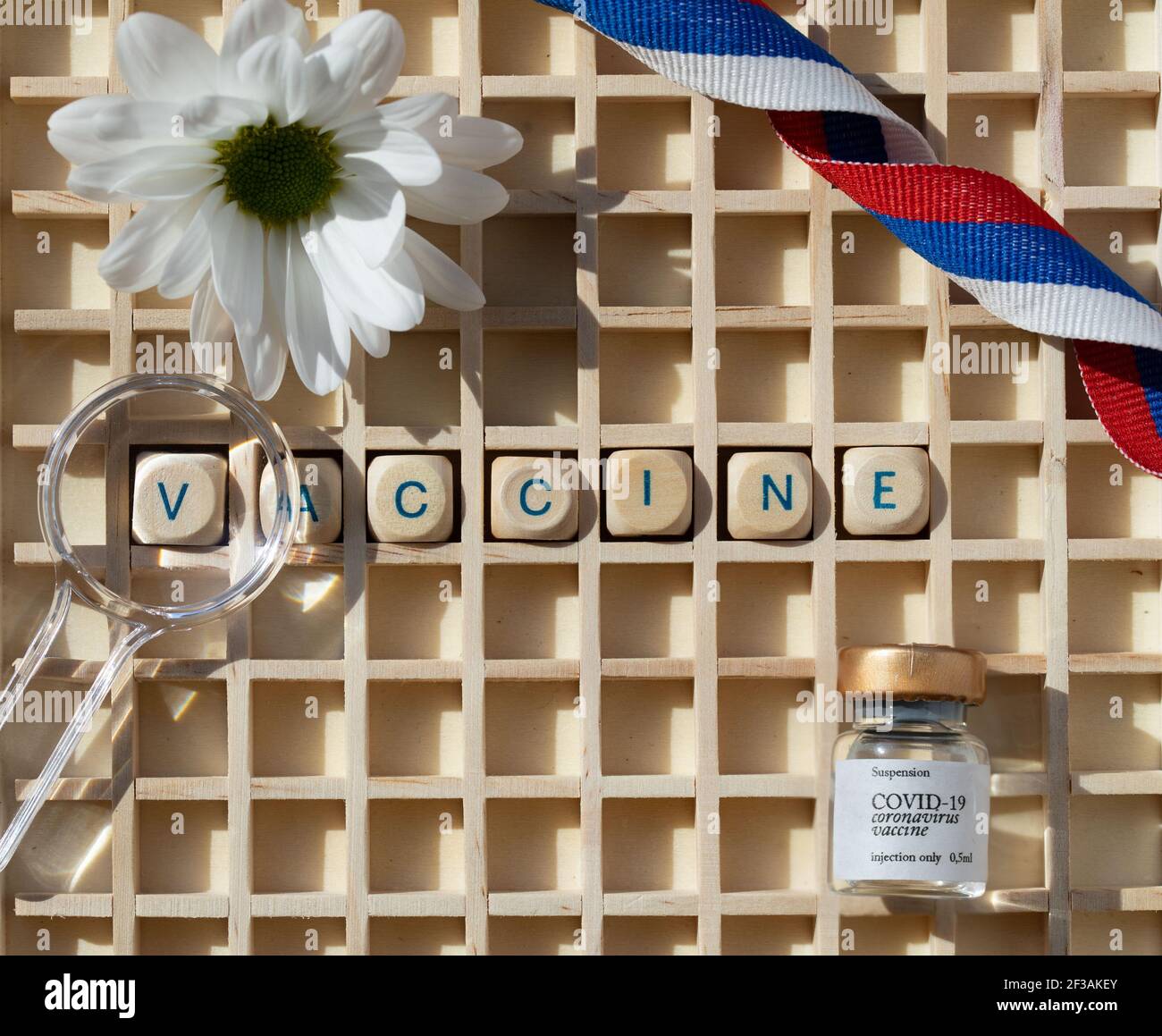 Word VACCINE composed of wooden letters. Vial with COVID19 vaccine and