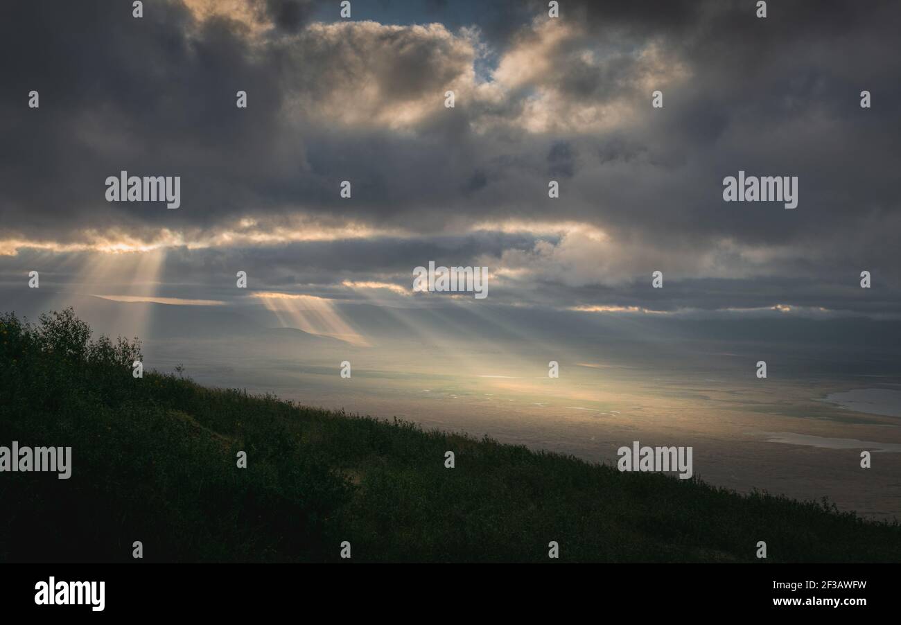 Rays of light through the clouds in Panoramic view of Ngorongoro Conservation Area at sunrise from the mountainside. Tanzania, Africa. Stock Photo