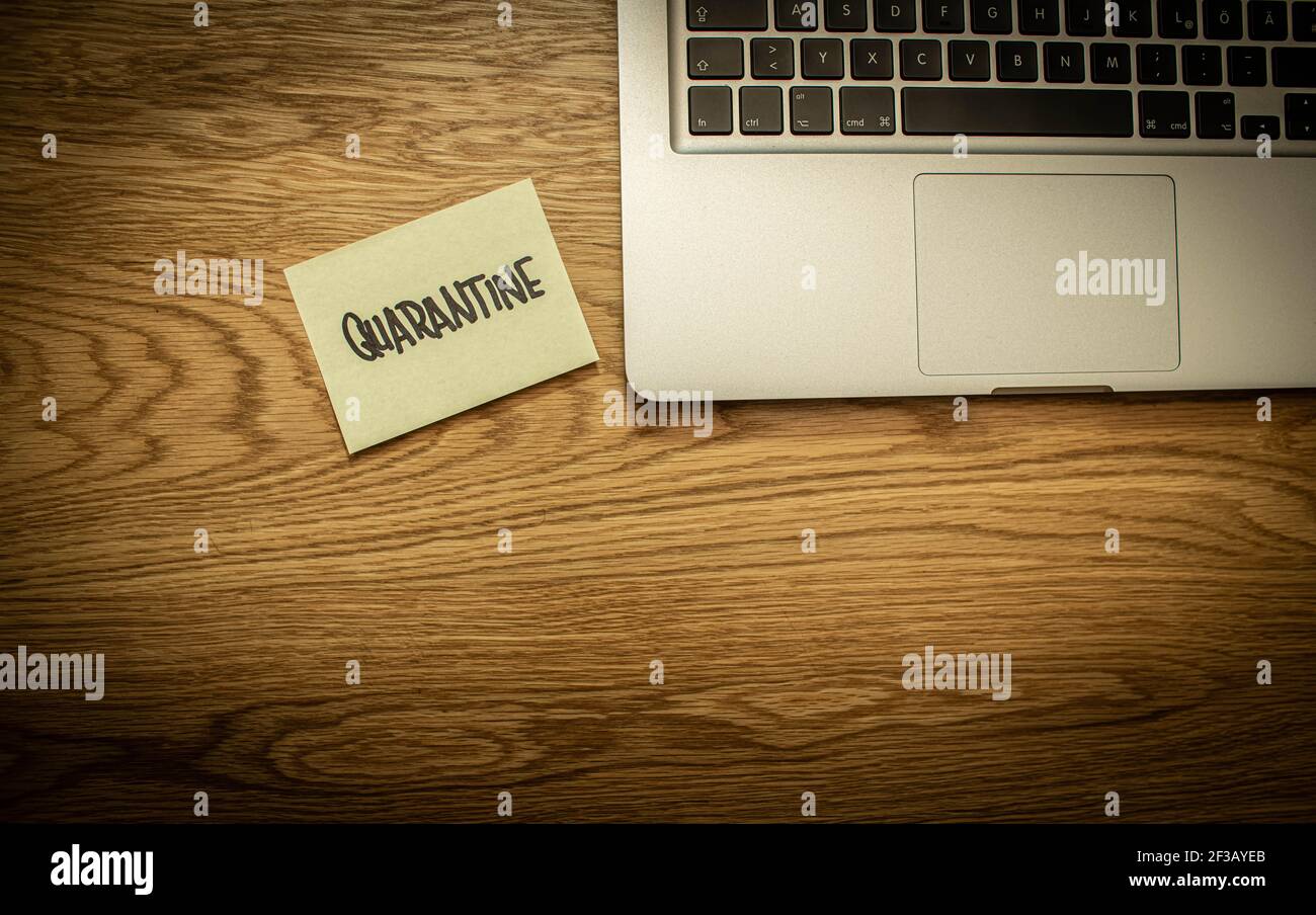 quarantine note in home office on wood table with computer Stock Photo