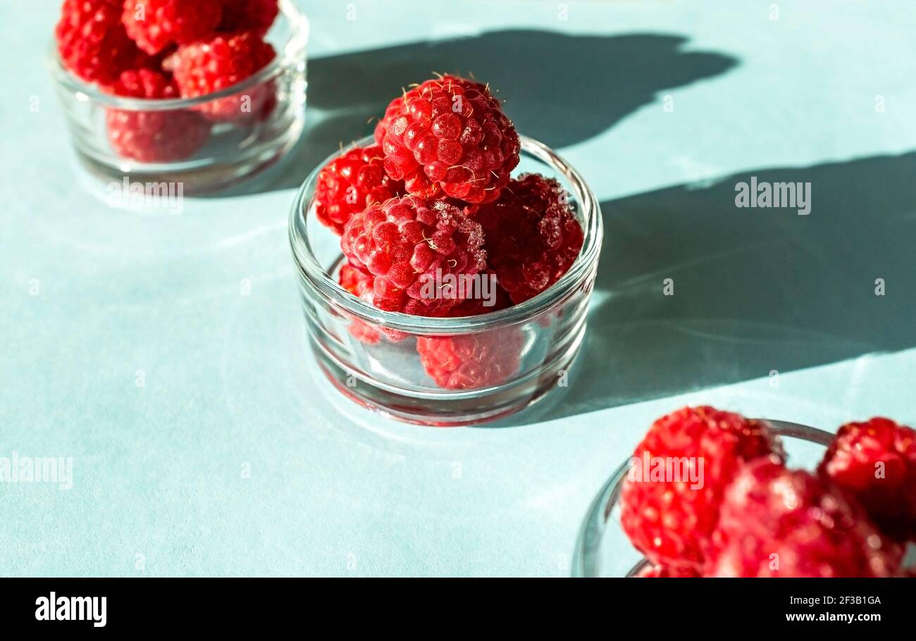 Frozen Raspberry Cups Frozen raspberries close-up in glass cups on a blue background close-up ...