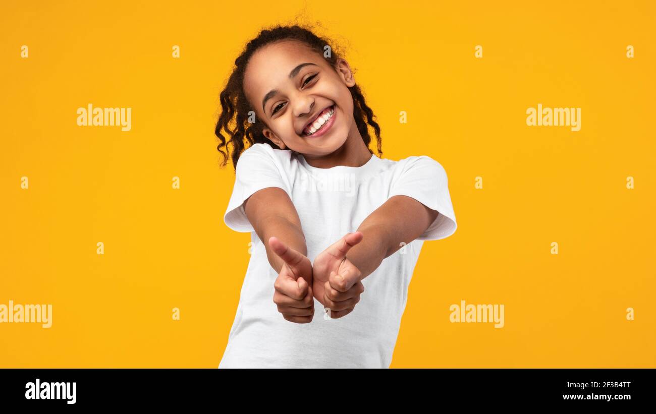 Happy black girl gesturing thumbs up and smiling Stock Photo - Alamy