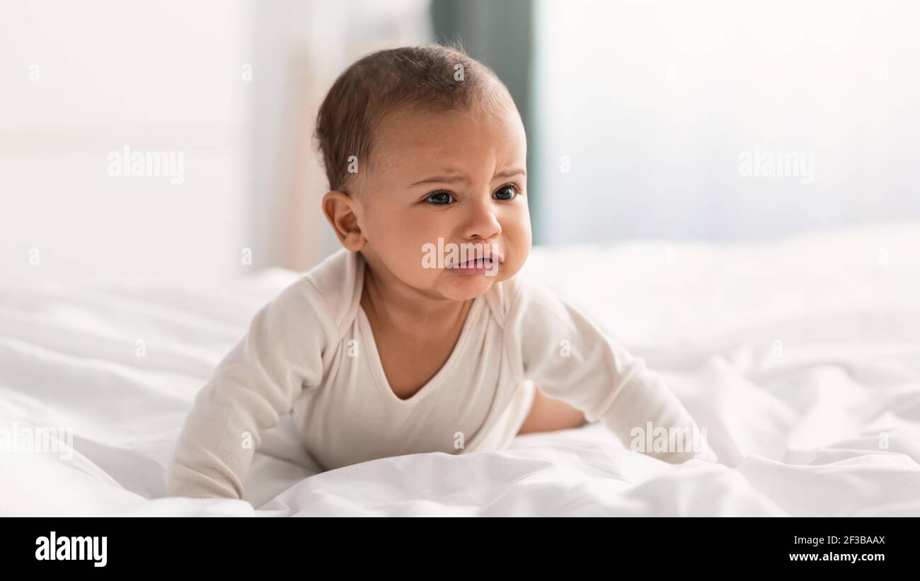 Portrait of sad black baby crying alone in bedroom Stock Photo