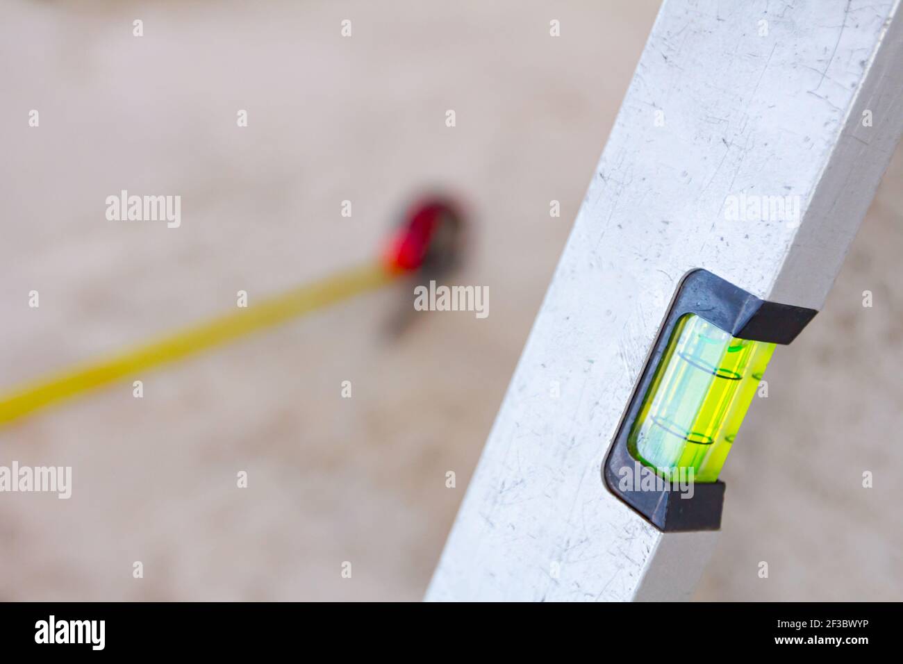 Spirit level placed next to the wall and metal measure tape is on the  concrete floor after usage for construction site for measurement and  control Stock Photo - Alamy