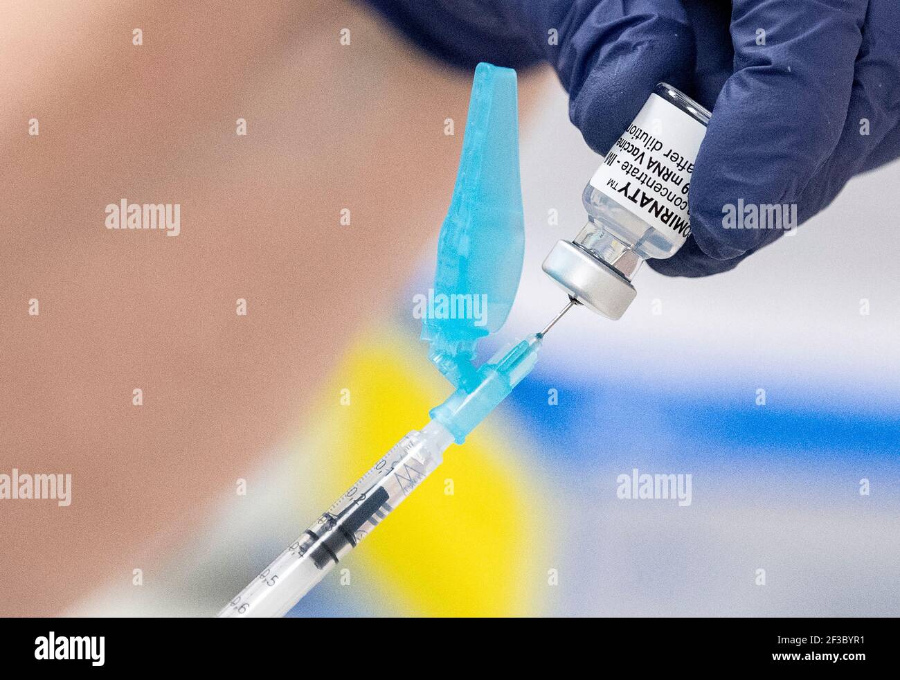 Gloved hands preparing a syringe with Comirnaty Covid-19 ...