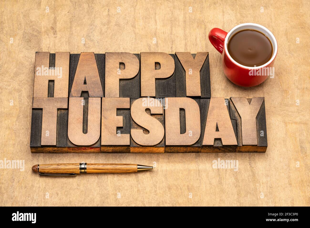 Happy Tuesday word abstract in vintage letterpress wood type against textured handmade paper with a cup of coffee, cheerful greetings Stock Photo