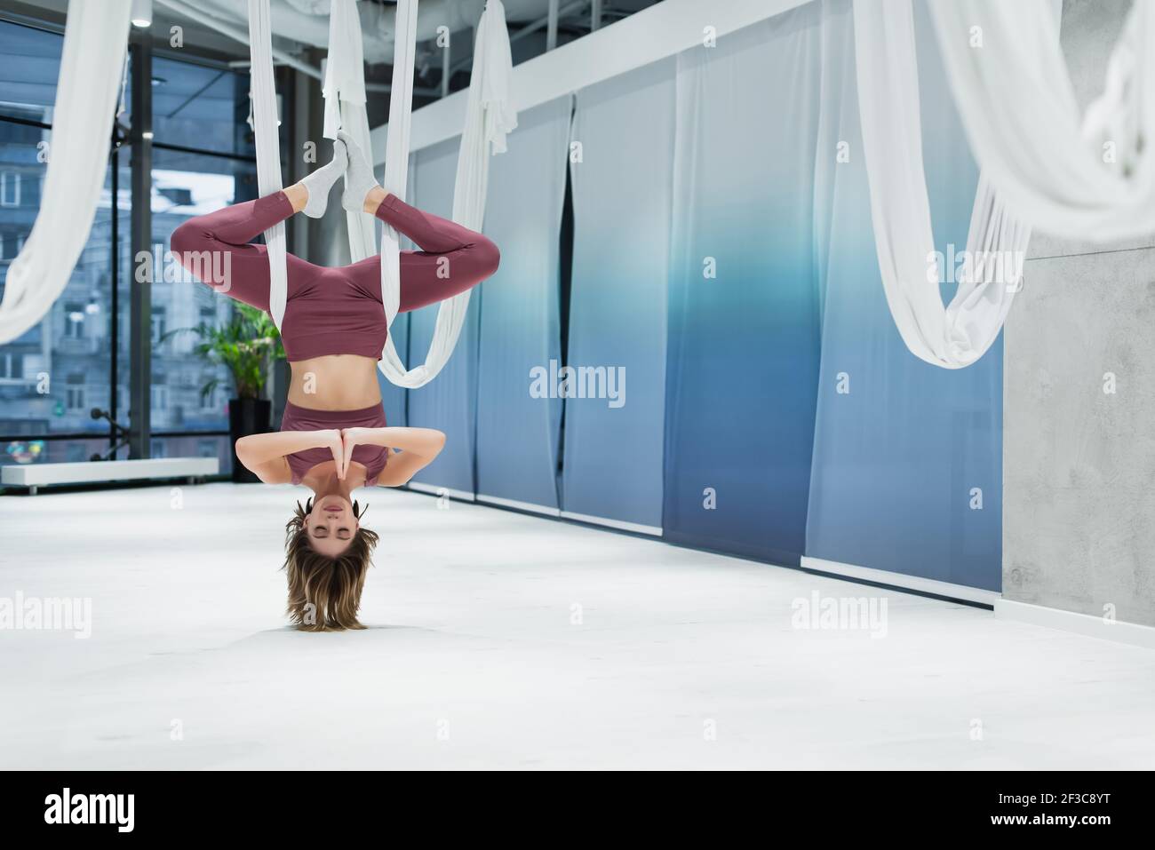 Sportswoman with praying hands practicing fly yoga in sports center Stock Photo