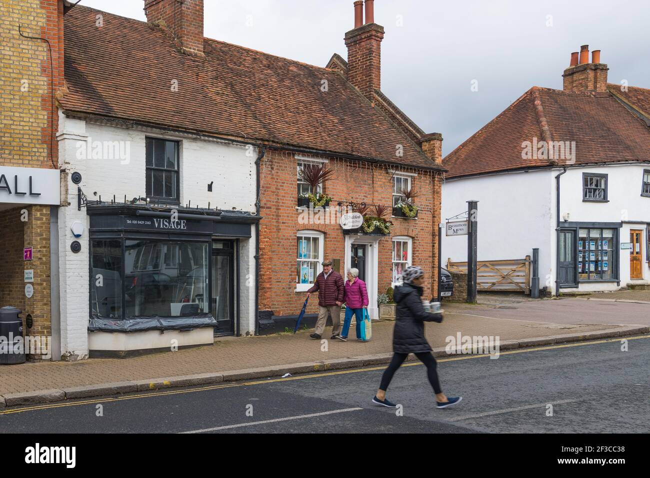 Senior man and woman walking in Pinner High Street. Young woman