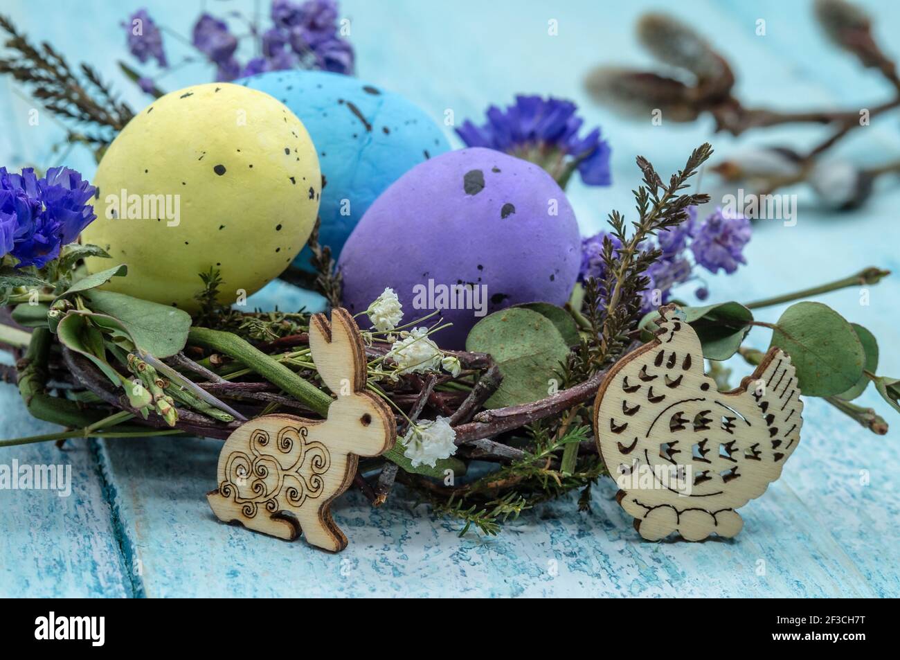 Happy Easter. A nest with Easter eggs. Willow twigs. Holy Easter. Blue background. Easter bunny and chicken. Stock Photo