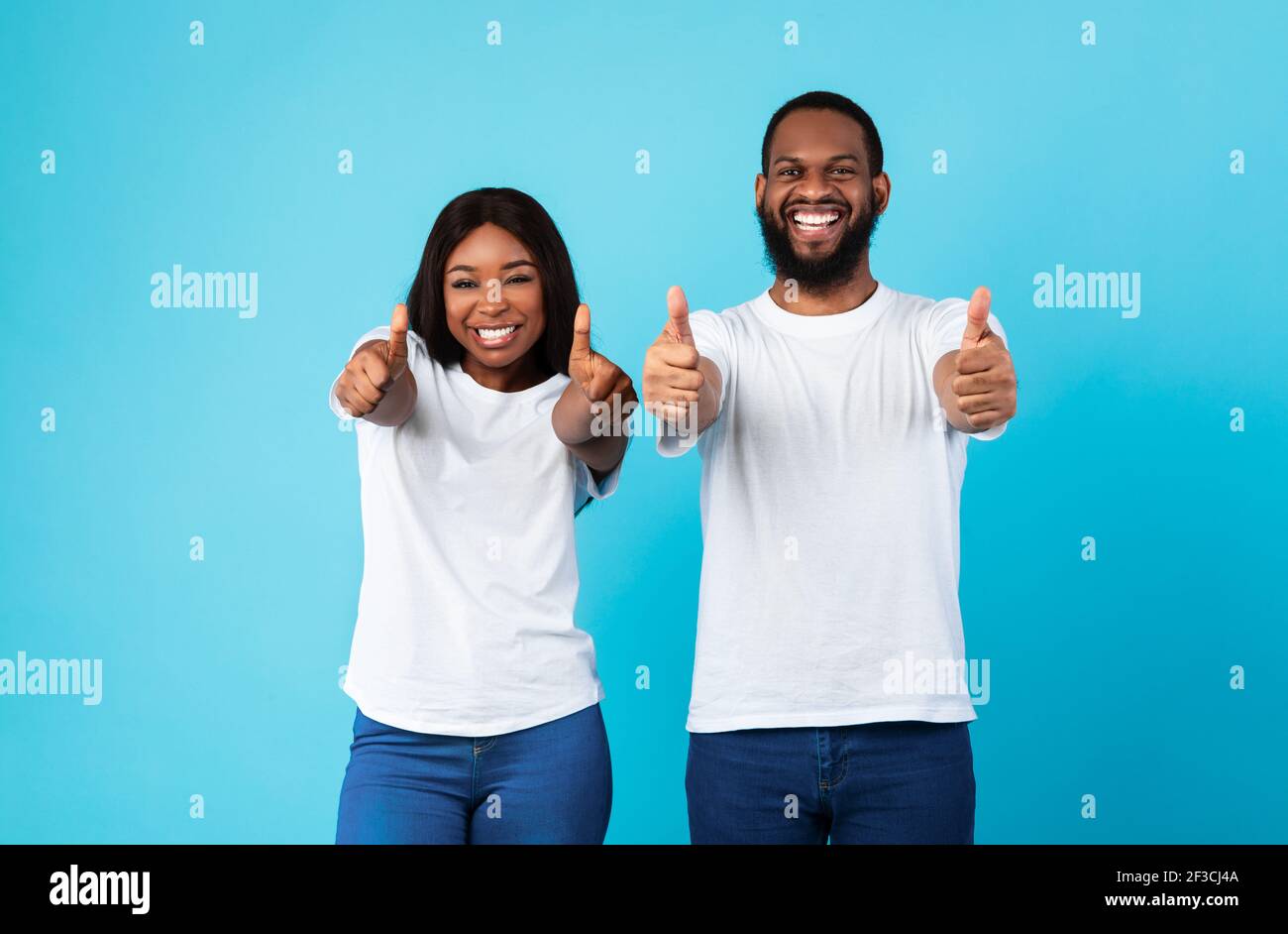 Happy black couple gesturing thumbs up and smiling Stock Photo